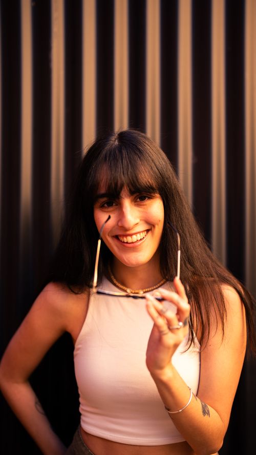 Free A cheerful woman posing with sunglasses against a striped background in Buenos Aires. Stock Photo