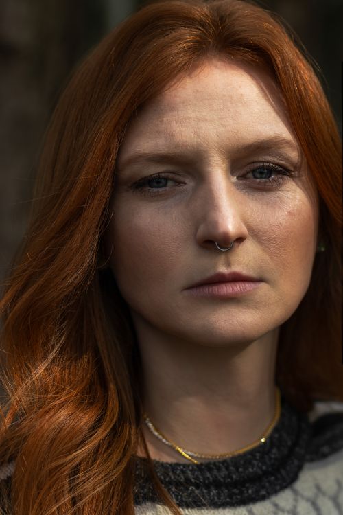 Free Close-up portrait of a woman with red hair and nose ring, gazing intently. Stock Photo