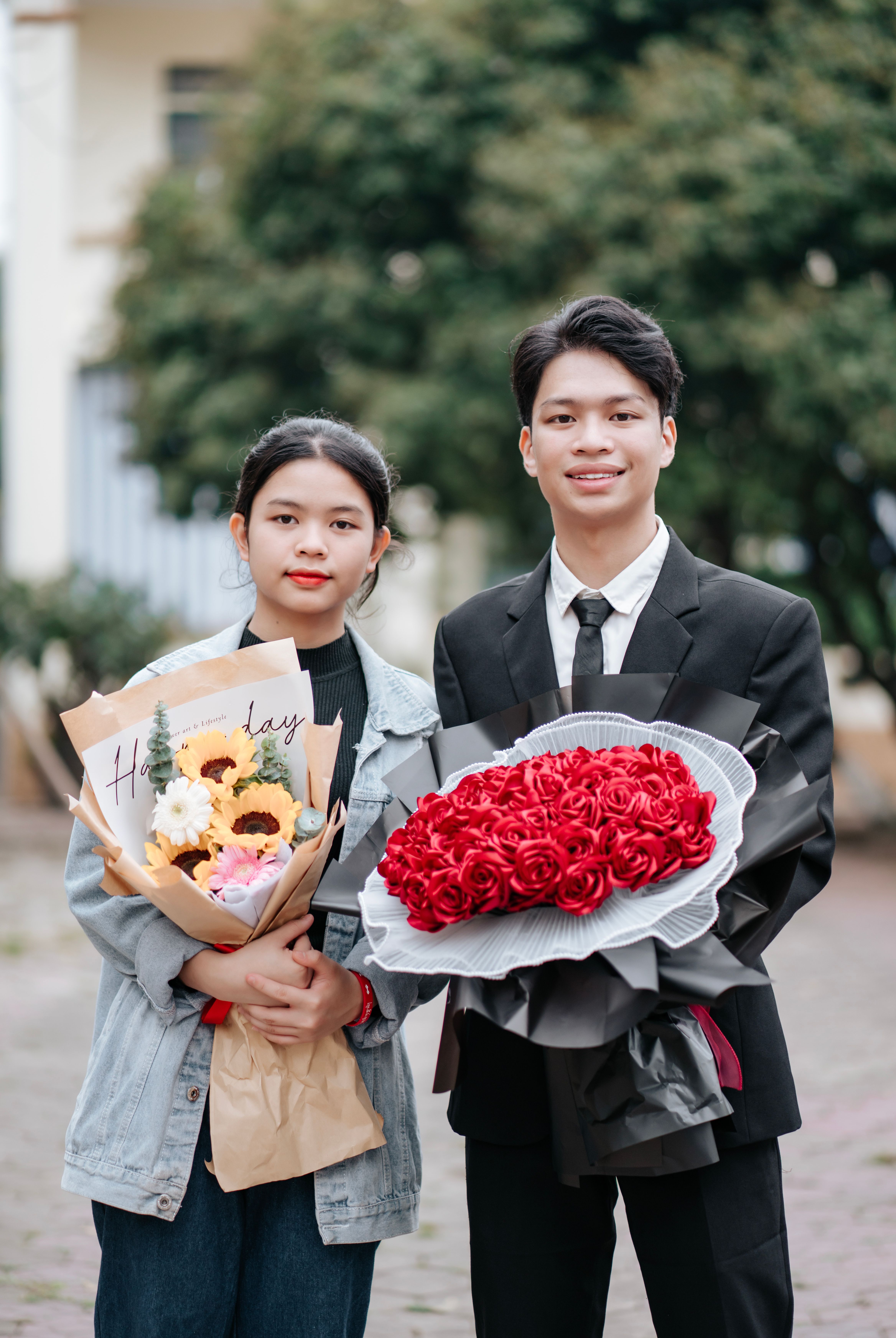 A young couple outdoors holding bouquets with a warm and vibrant mood.