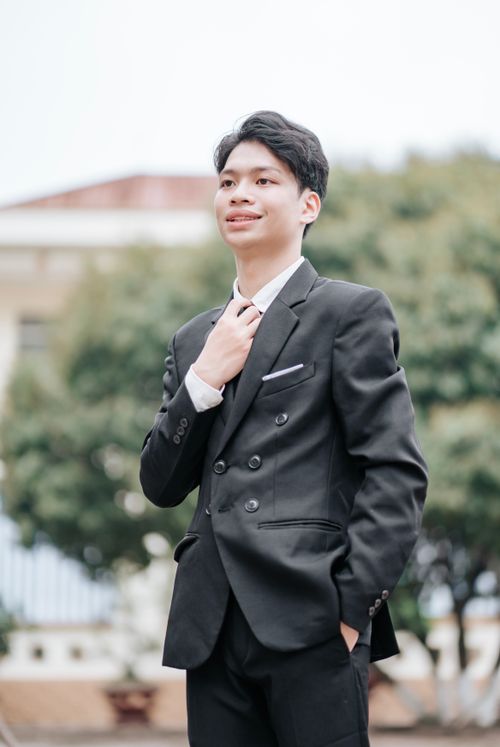 Free Young man in a black suit adjusting his tie outdoors, exuding confidence. Stock Photo