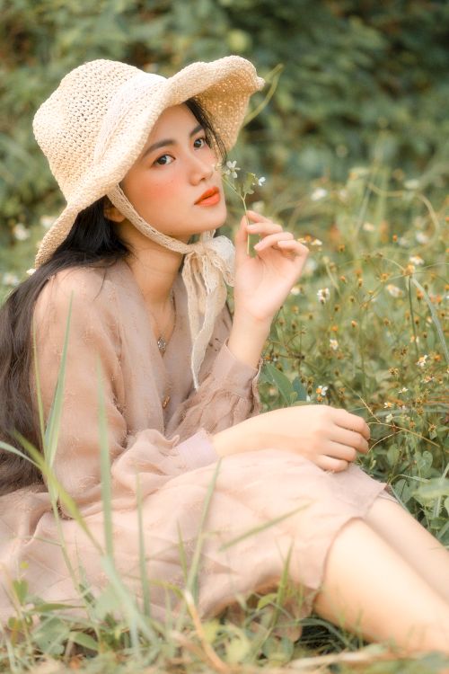 Free A captivating portrait of a woman in a sun hat surrounded by wildflowers, exuding elegance and nature's tranquility. Stock Photo