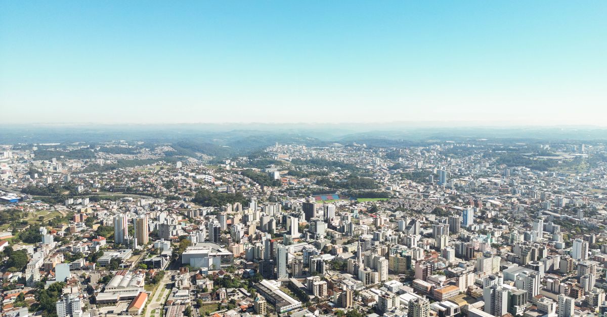 Stunning aerial view of Caxias do Sul's urban cityscape under a clear blue sky.