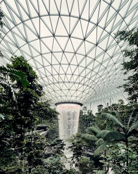 View of the stunning indoor waterfall at Jewel Changi Airport in Singapore, surrounded by lush greenery.