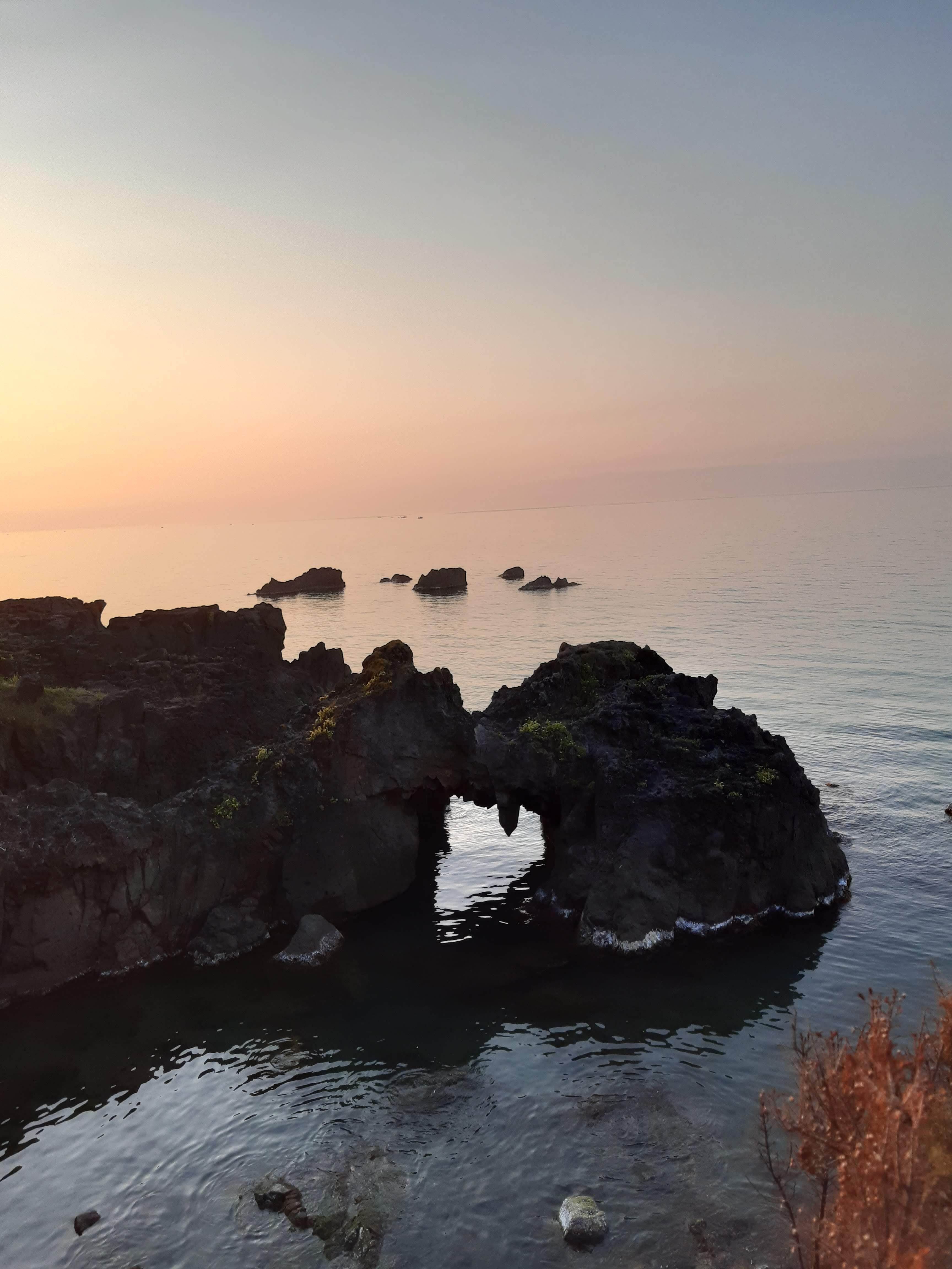 Serene Coastal Rock Formation at Sunset · Free Stock Photo