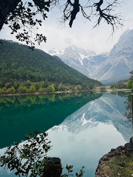 Serene view of pristine lake reflecting snow-capped mountains and lush forest.