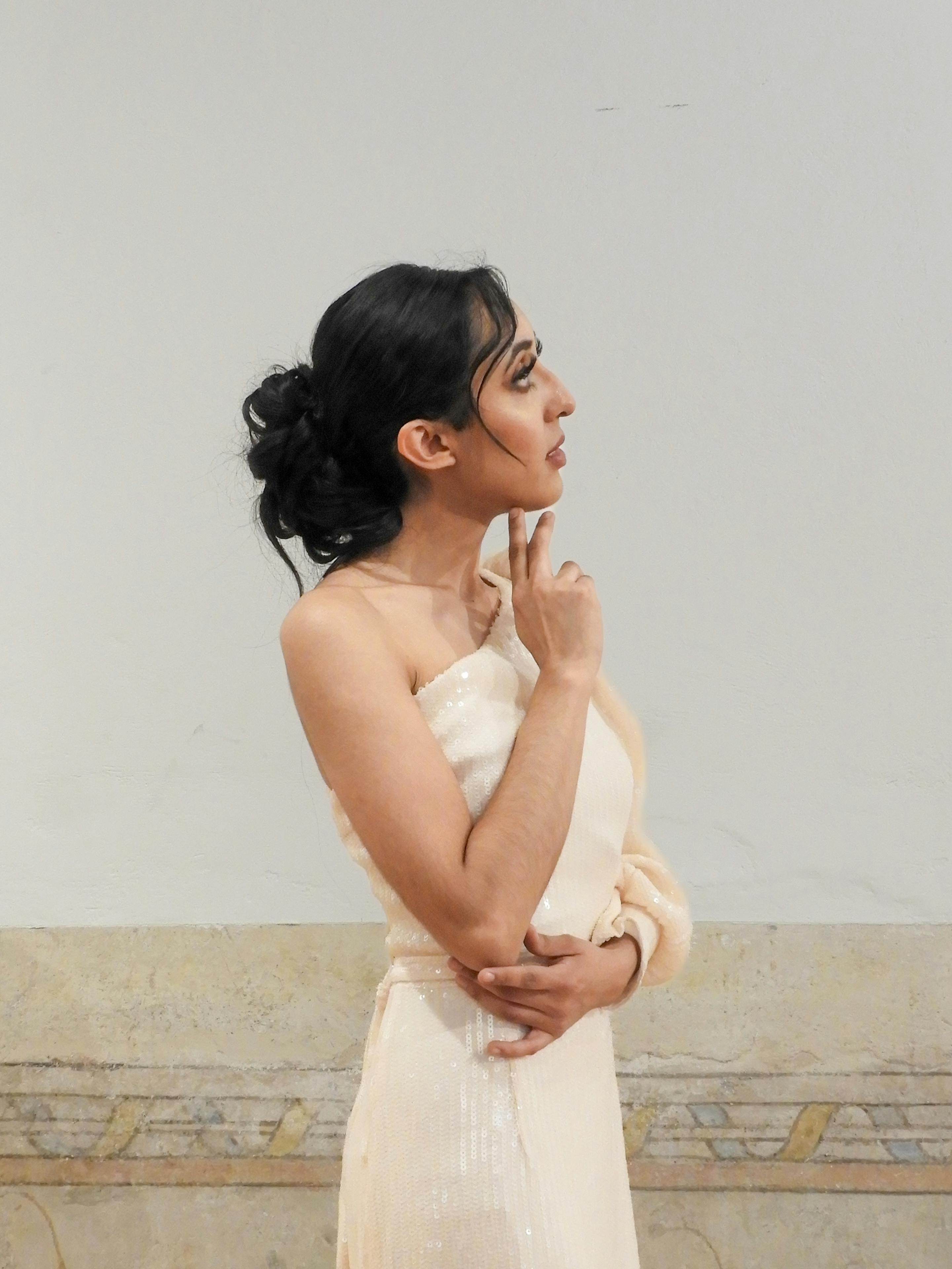 Model posing elegantly against a simple backdrop, showcasing fashion and beauty.