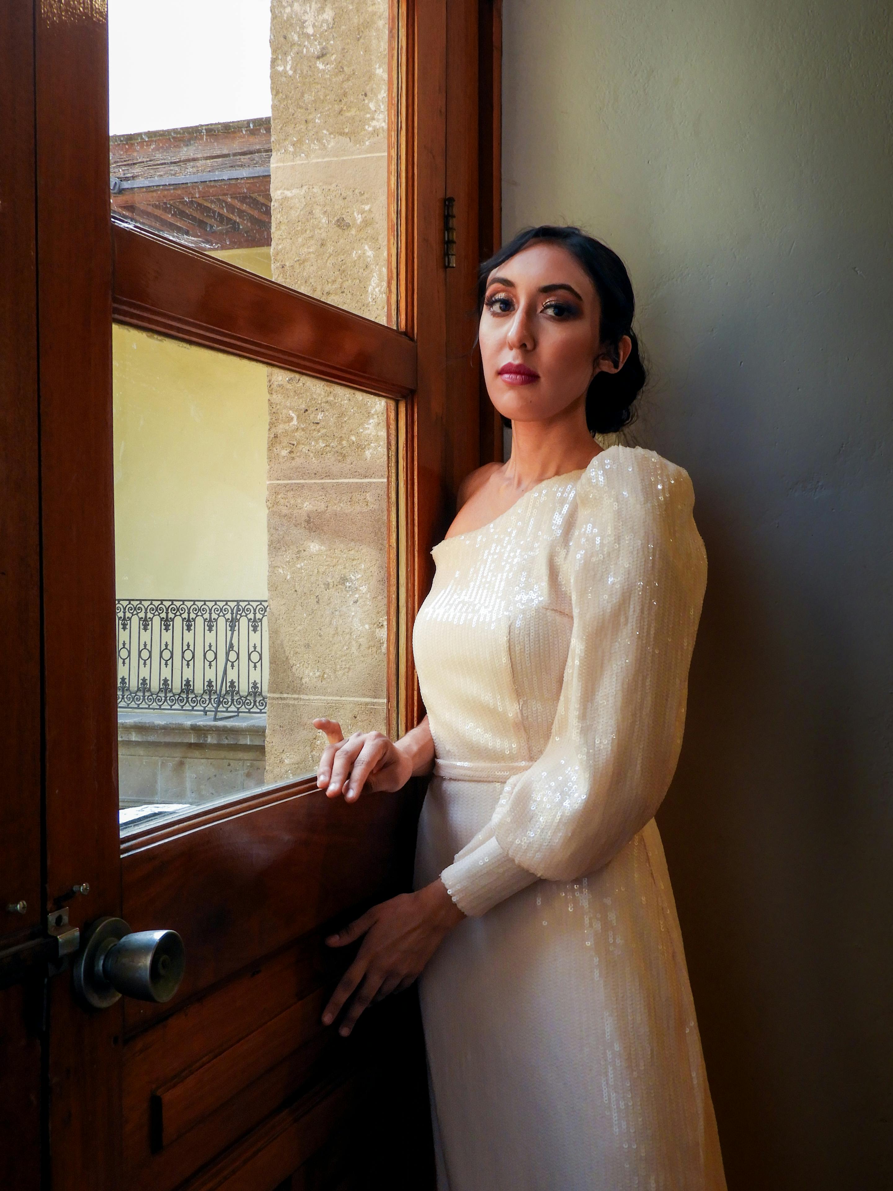 elegant woman in sequin dress by window