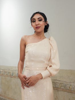 Elegant woman in a stylish one-shoulder gown posing indoors.