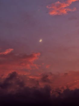 A stunning crescent moon amidst a vibrant sky painted in shades of pink and purple.