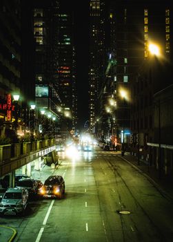 Dynamic cityscape at night with illuminated skyscrapers and cars.