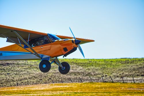 Free An orange airplane soars above the countryside on a bright, clear day. Stock Photo