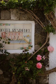 Charming stone wall with colorful flowers and a vintage hotel residence sign.