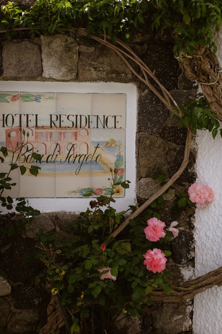 Charming stone wall with colorful flowers and a vintage hotel residence sign.