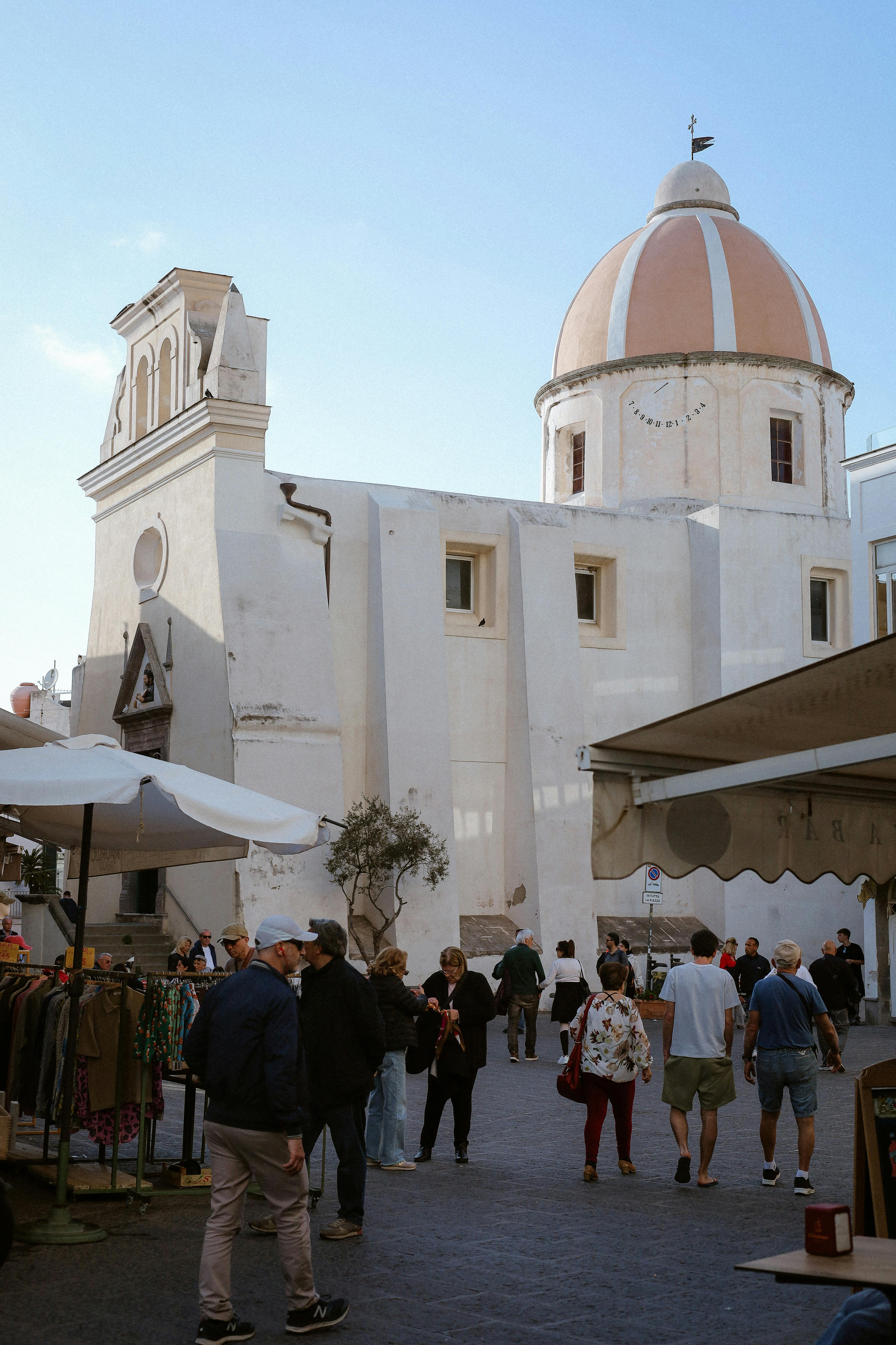 Busy market scene with people near a historic church in Italy.