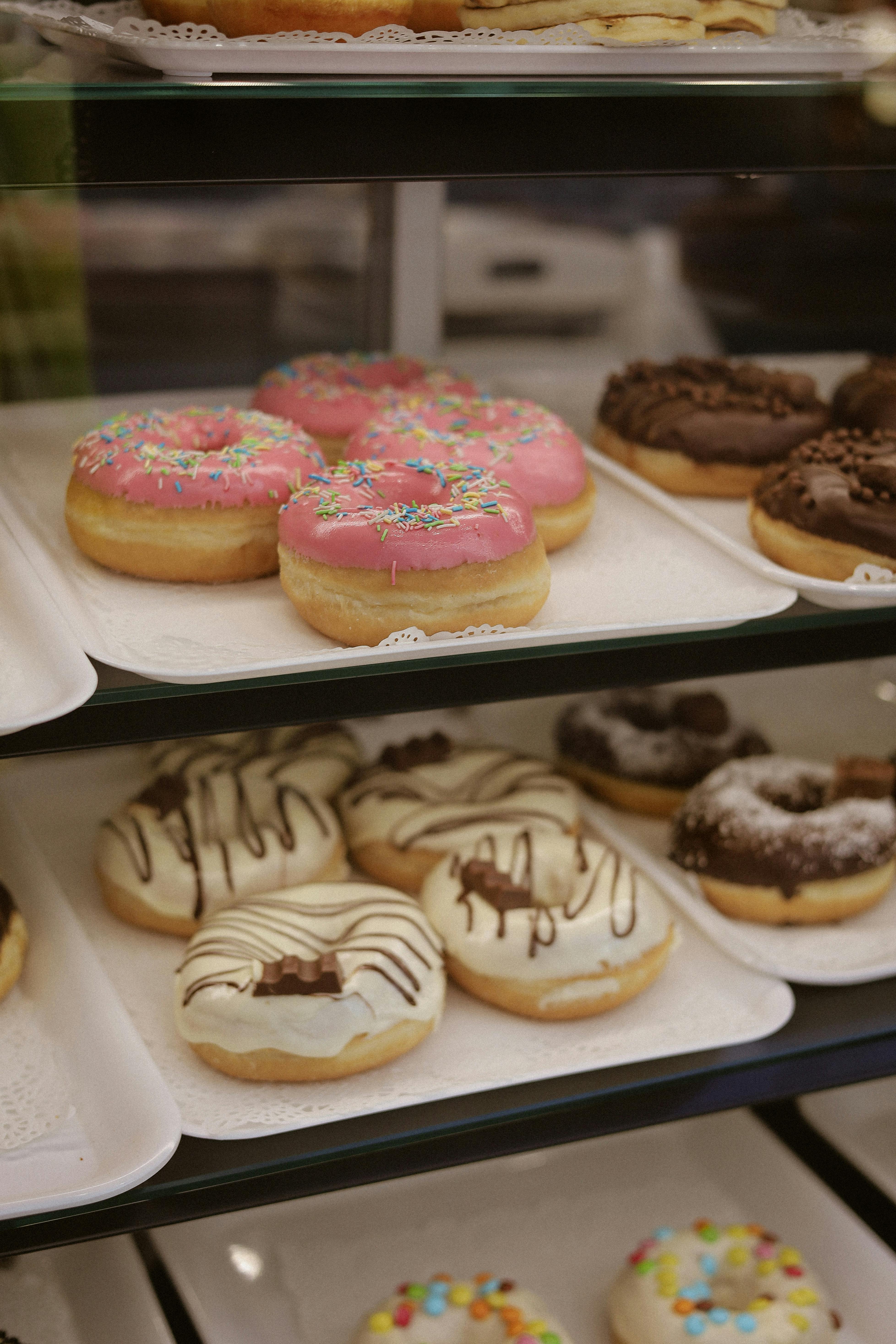 A tempting variety of colorful and delicious donuts on display in a bakery case.