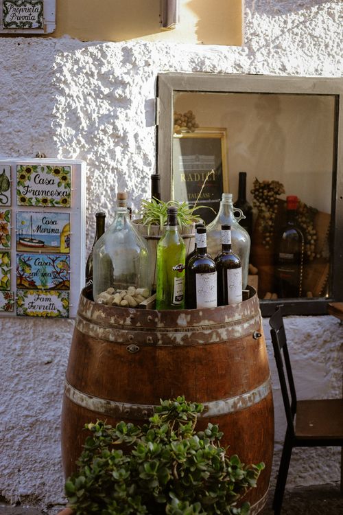 Free Outdoor display of wine bottles on a rustic barrel with vibrant natural lighting. Stock Photo
