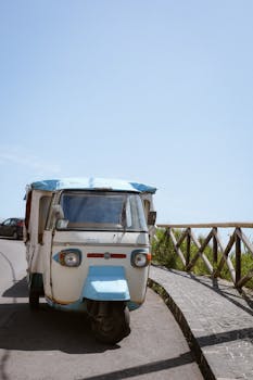 A classic Tuk Tuk parked on a sunny street with clear blue skies.