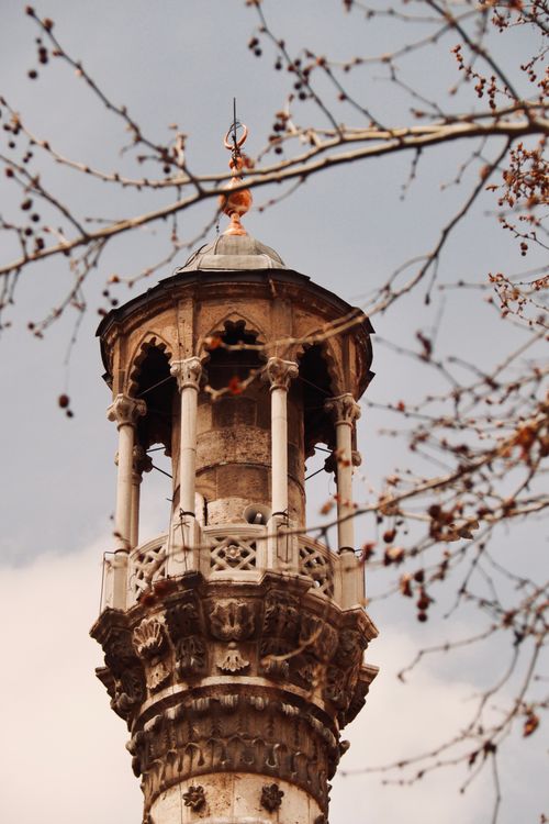 Free A detailed view of an ancient minaret in Konya, Türkiye framed by autumn branches. Stock Photo