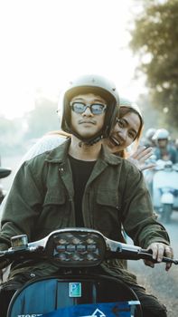 Friends enjoying a Vespa ride during a sunny day in East Java, Indonesia.