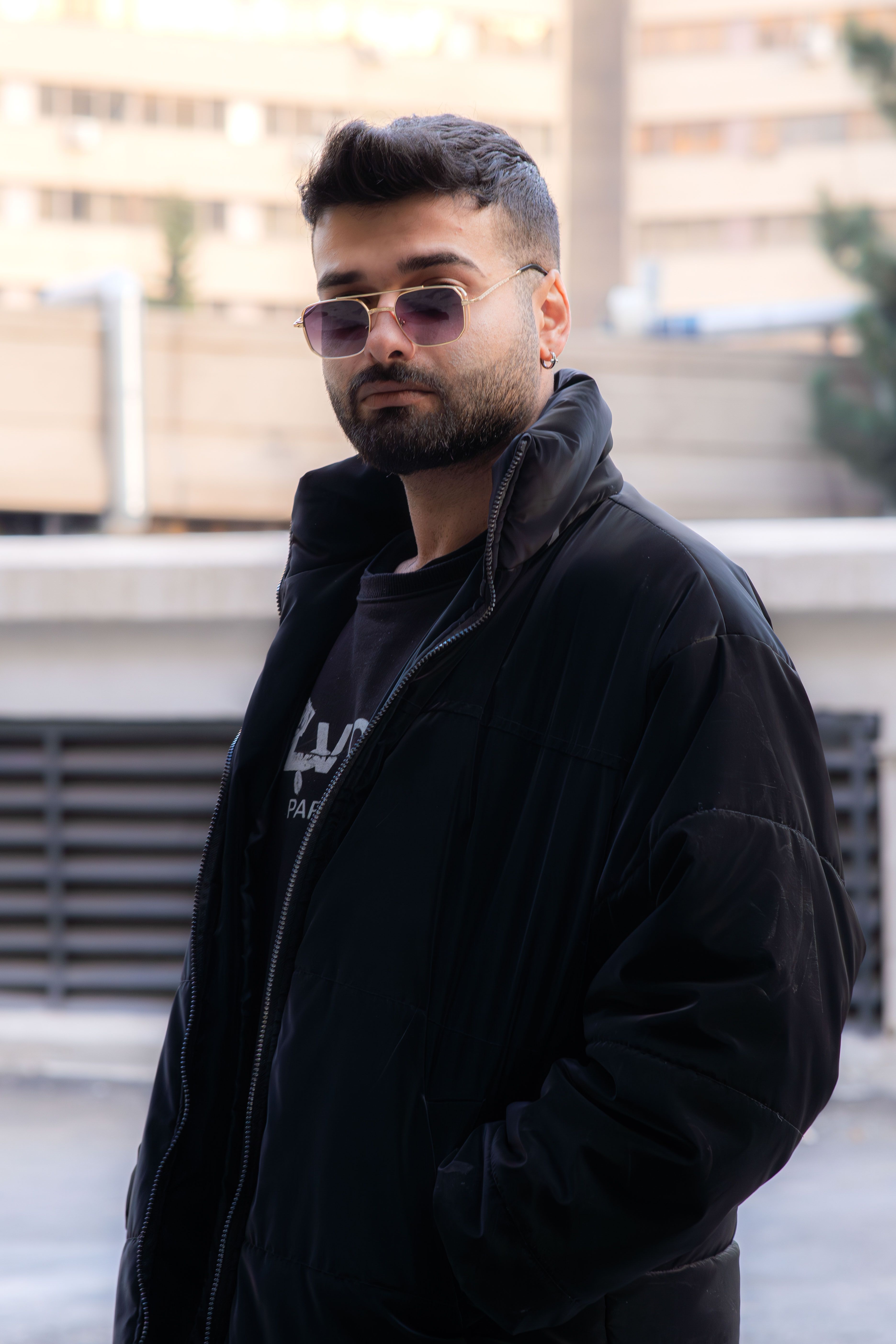 Stylish man with sunglasses in urban Tehran setting, exuding modern fashion.