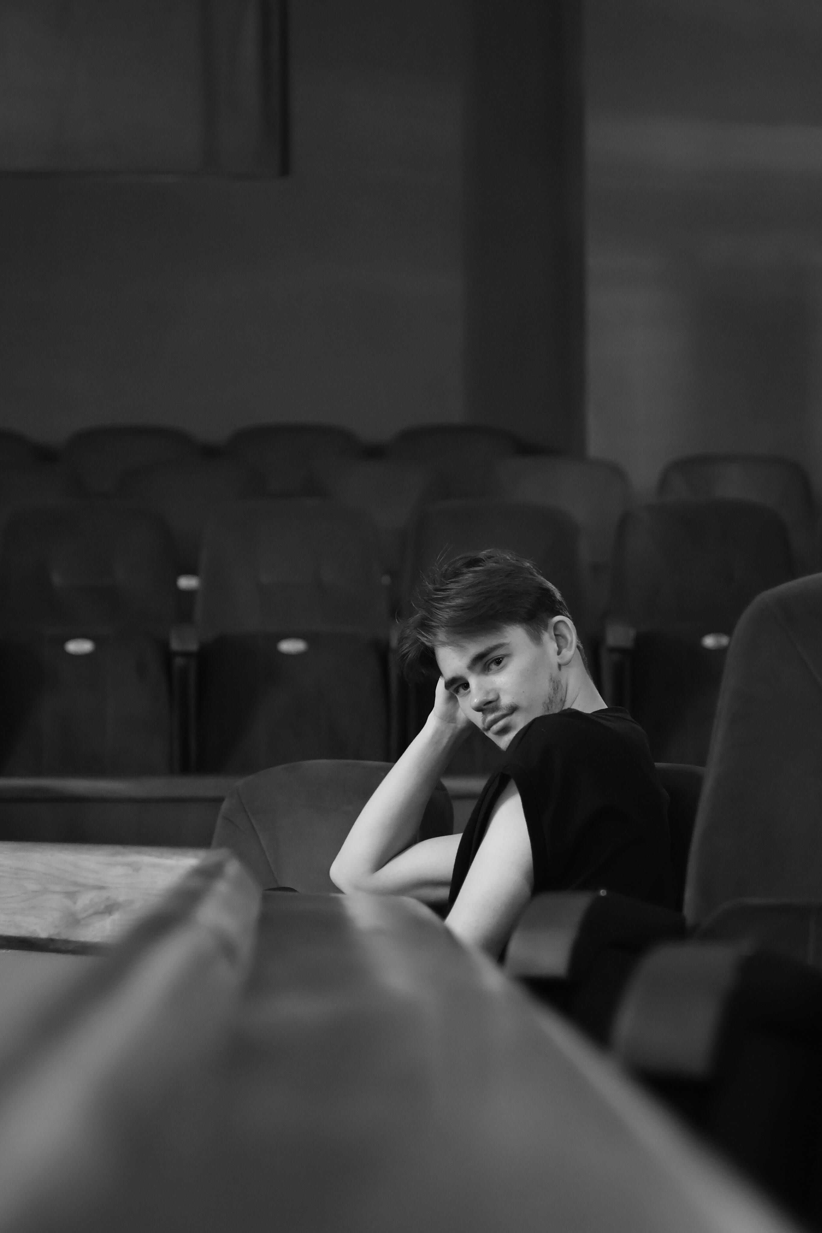 Free Black and white photo of a person sitting in an empty theater, looking contemplative. Stock Photo