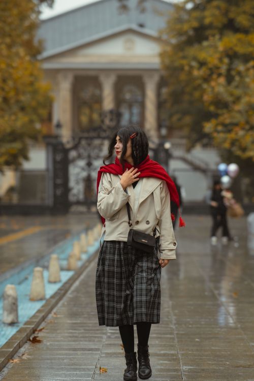 Woman styling plaid skirt on city street
