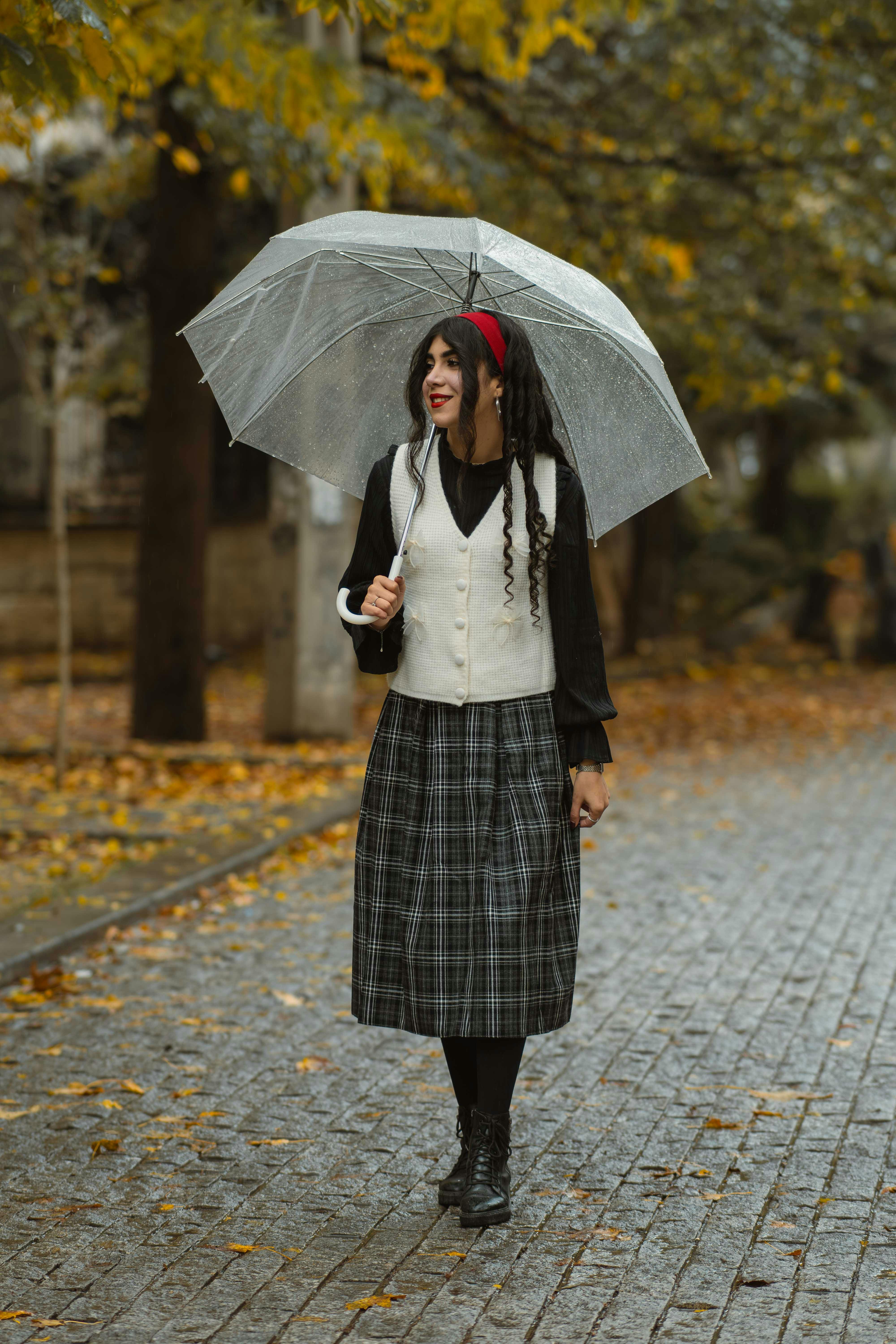 grátis Uma mulher elegante com um guarda-chuva passeia por uma rua chuvosa de outono, aproveitando o clima frio. Foto profissional