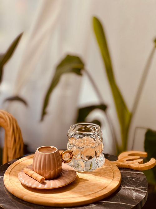 Free A cozy coffee setup with decorative glass and cup on a wooden tray in a warm, muted ambiance. Stock Photo