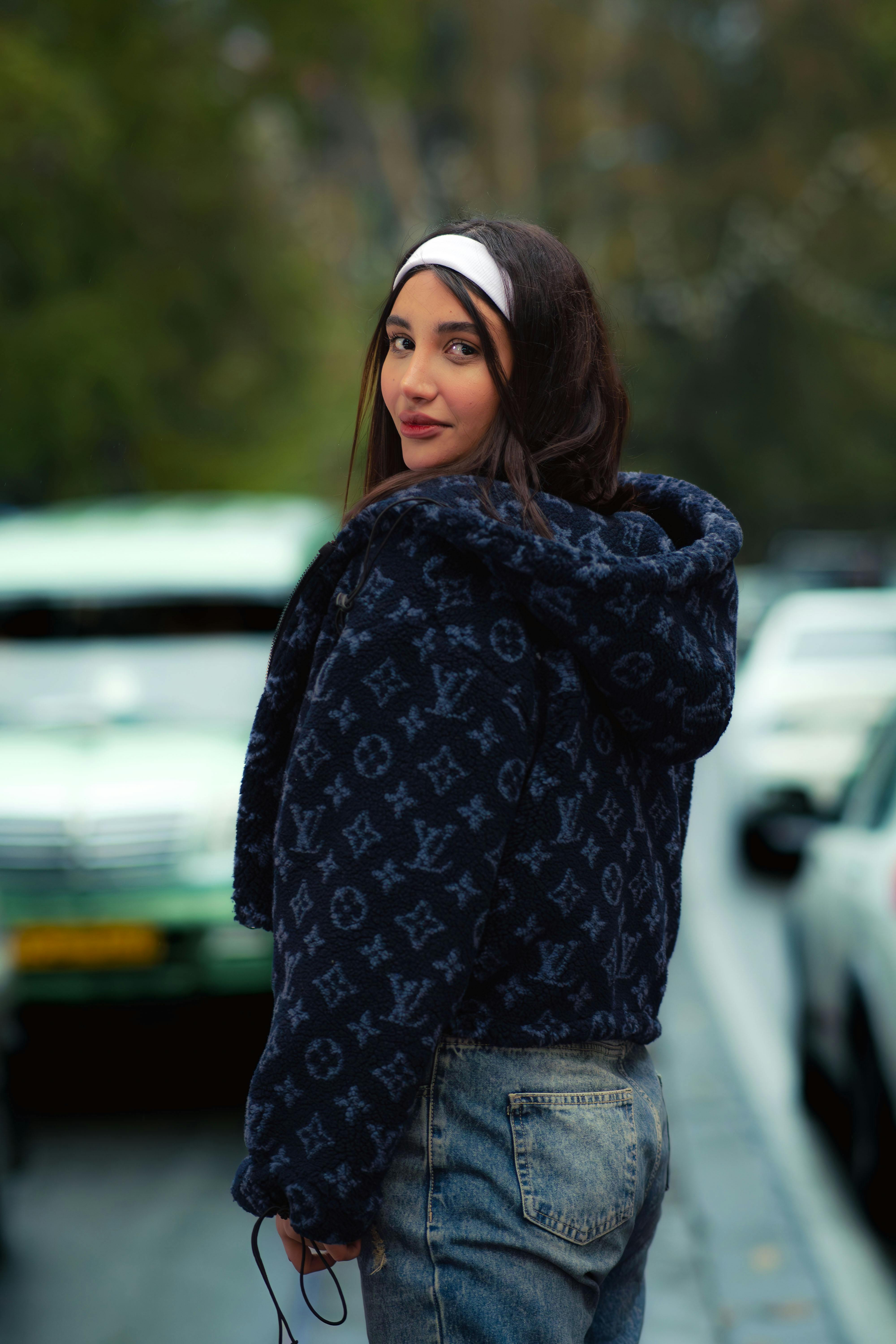 Free A fashionable woman in Tehran wearing a trendy jacket and jeans, looking over her shoulder. Stock Photo