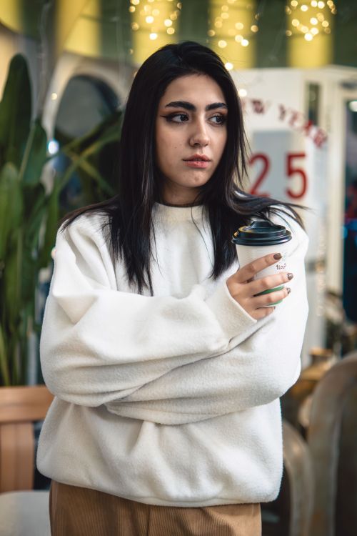 Free Stylish young woman holding a coffee cup in a modern Tehran café. Stock Photo