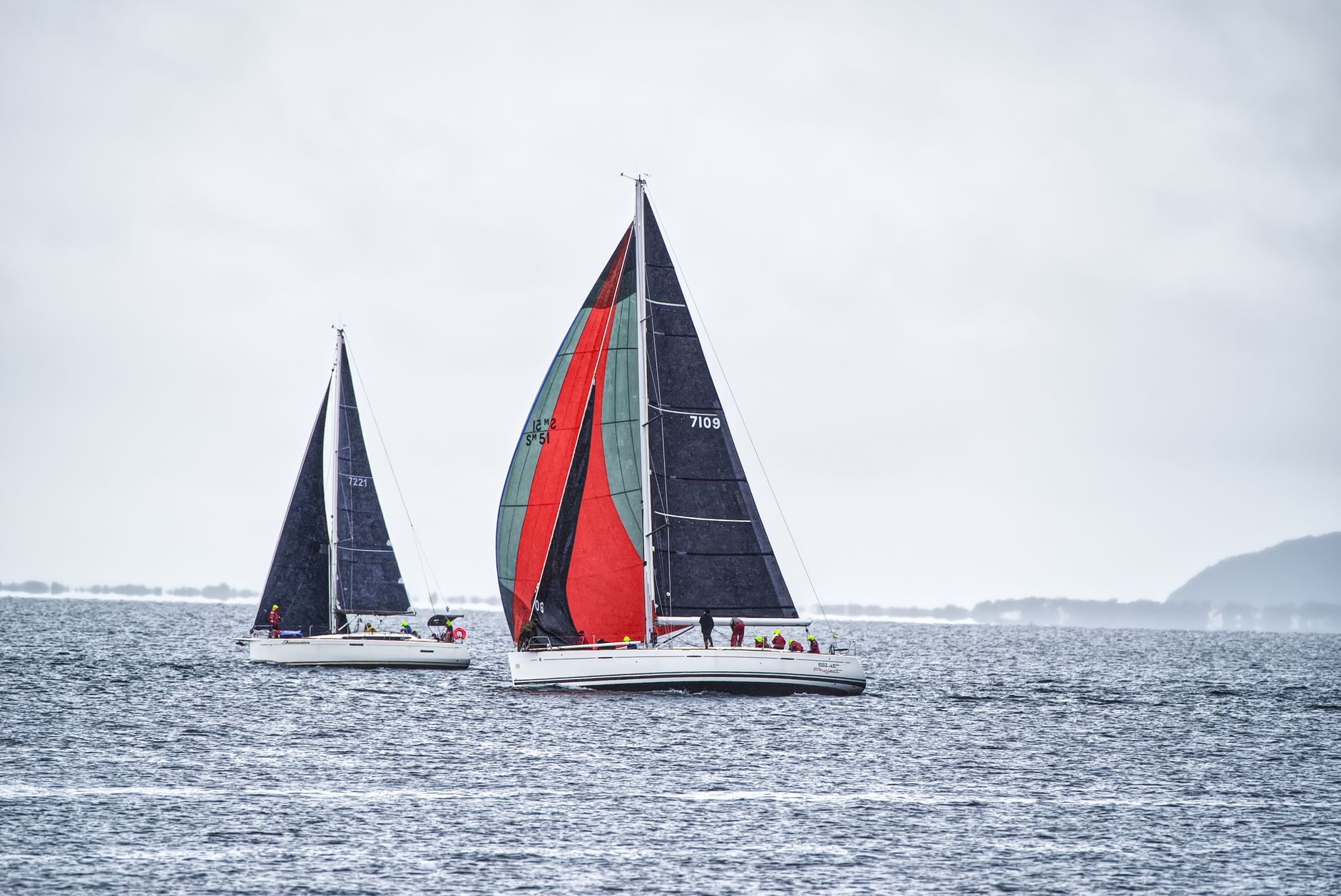 Two sailboats racing in open sea with colorful sails under a cloudy sky. — free online jigsaw puzzle on JigsawPuzzlesFreeOnline.org