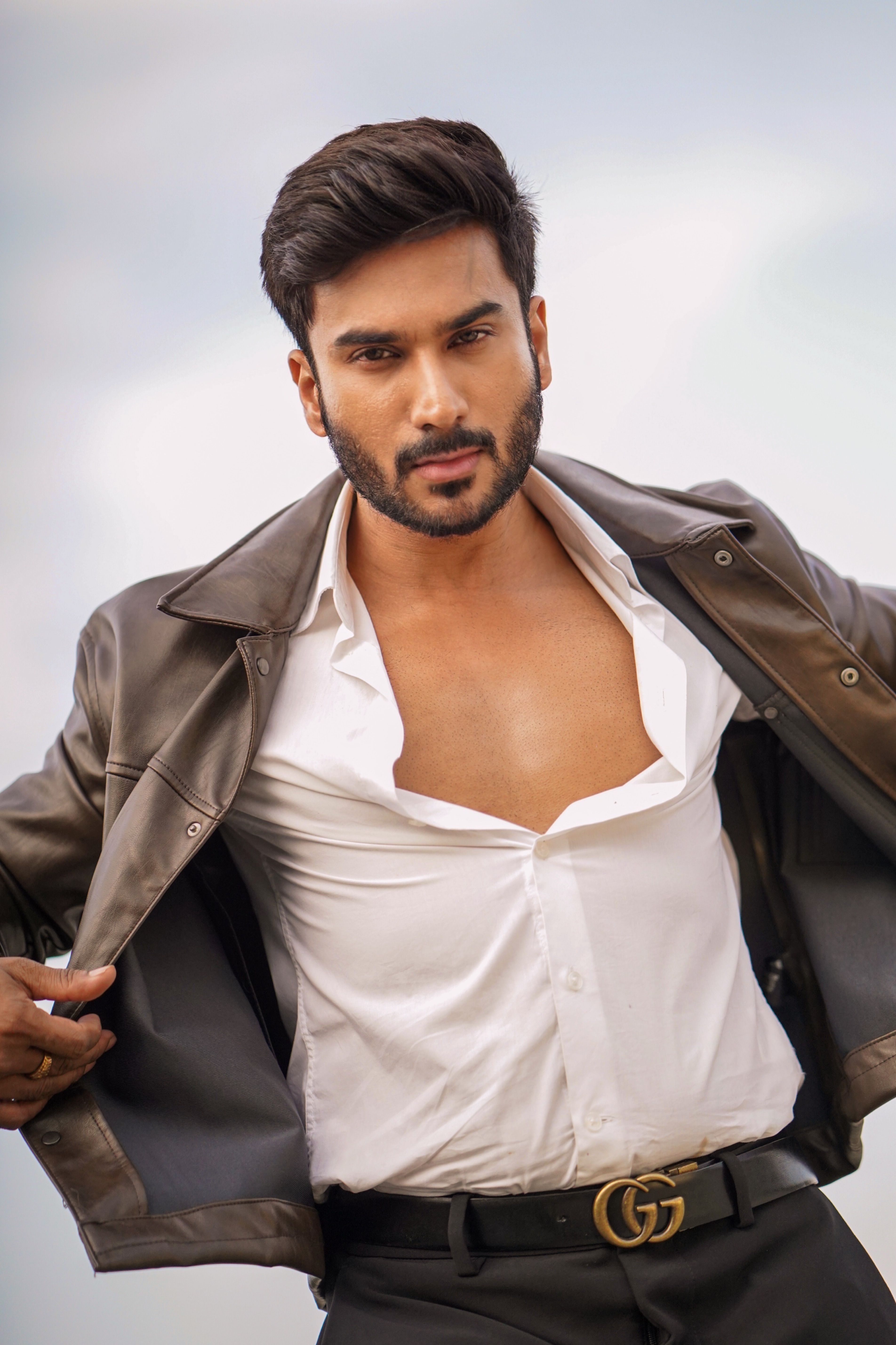 Portrait of a confident man in a leather jacket with an open shirt outdoors.