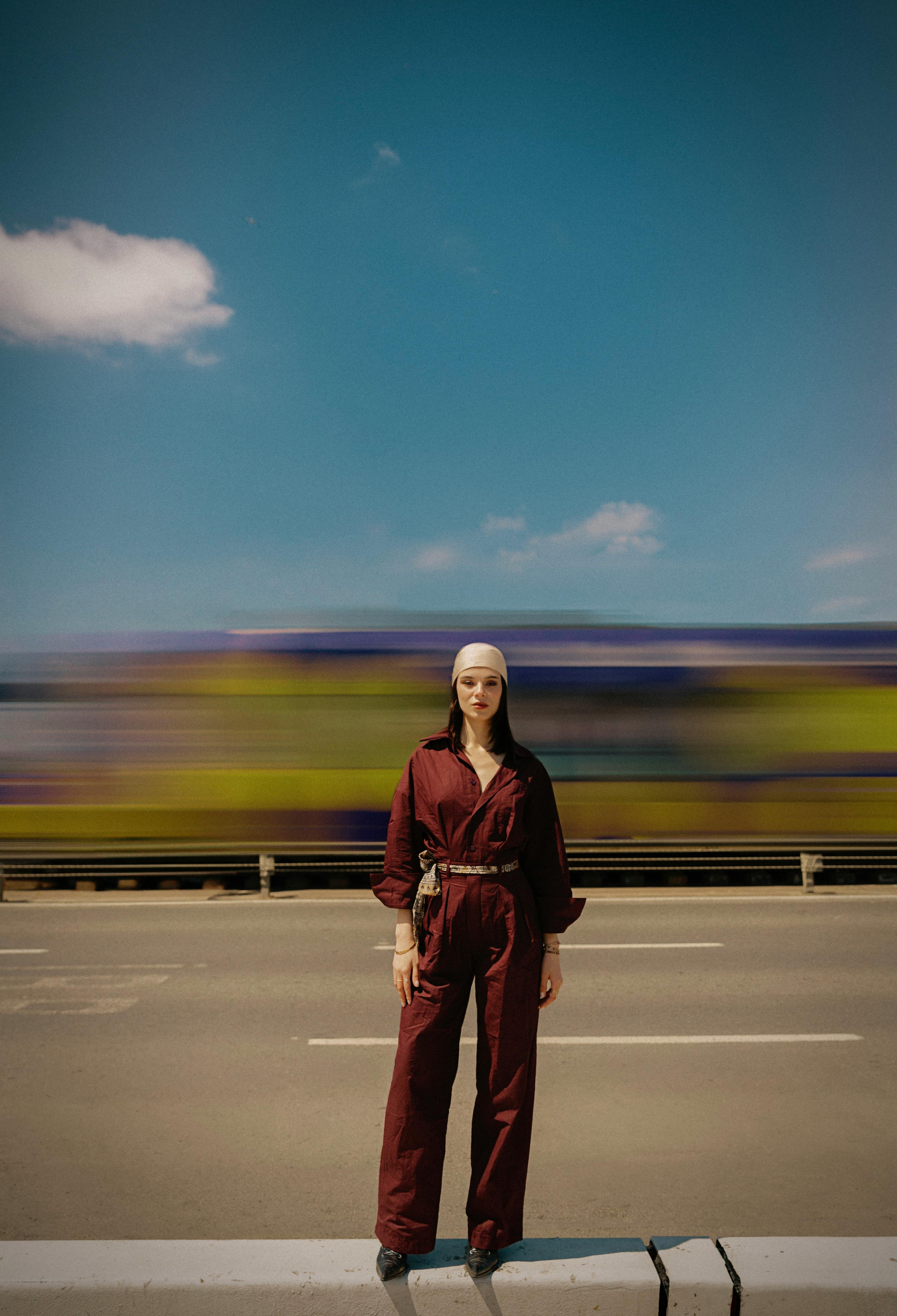 Fashionable woman in stylish attire posing with blurred bus in background on an İstanbul street.