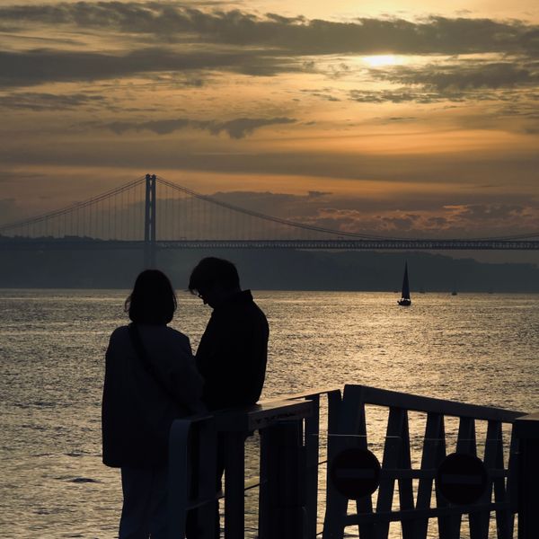 Two people at a riverside railing at sunset — photo by Bento Justin on Pexels
