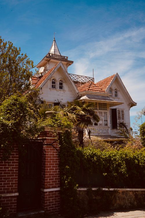 Free Beautiful Victorian house surrounded by lush green garden under a clear blue sky. Stock Photo