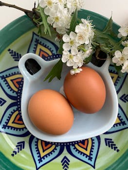 Colorful composition of brown eggs and white blossoms on a decorative plate, ideal for spring themes.