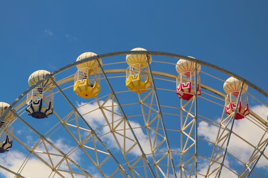 Vibrant Ferris wheel with colorful cabins set against a clear blue sky.