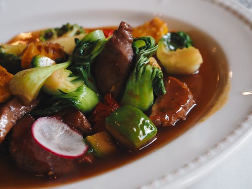 Free Close-up of a savory Asian stir-fry with assorted vegetables and meat, garnished with sauce. Stock Photo
