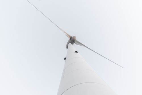 Free Close-up of a tall wind turbine viewed from below against a minimalistic sky. Stock Photo