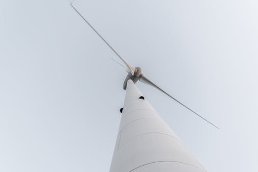 A minimalistic shot of a wind turbine captured from below, highlighting renewable energy against a clear sky.