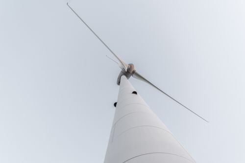 Free A minimalistic shot of a wind turbine captured from below, highlighting renewable energy against a clear sky. Stock Photo