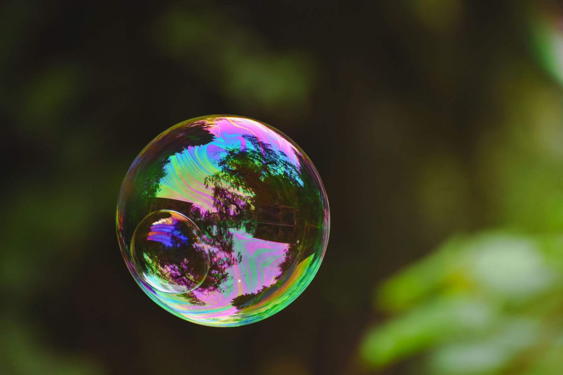 A vibrant iridescent soap bubble floating gently outdoors with natural reflections.