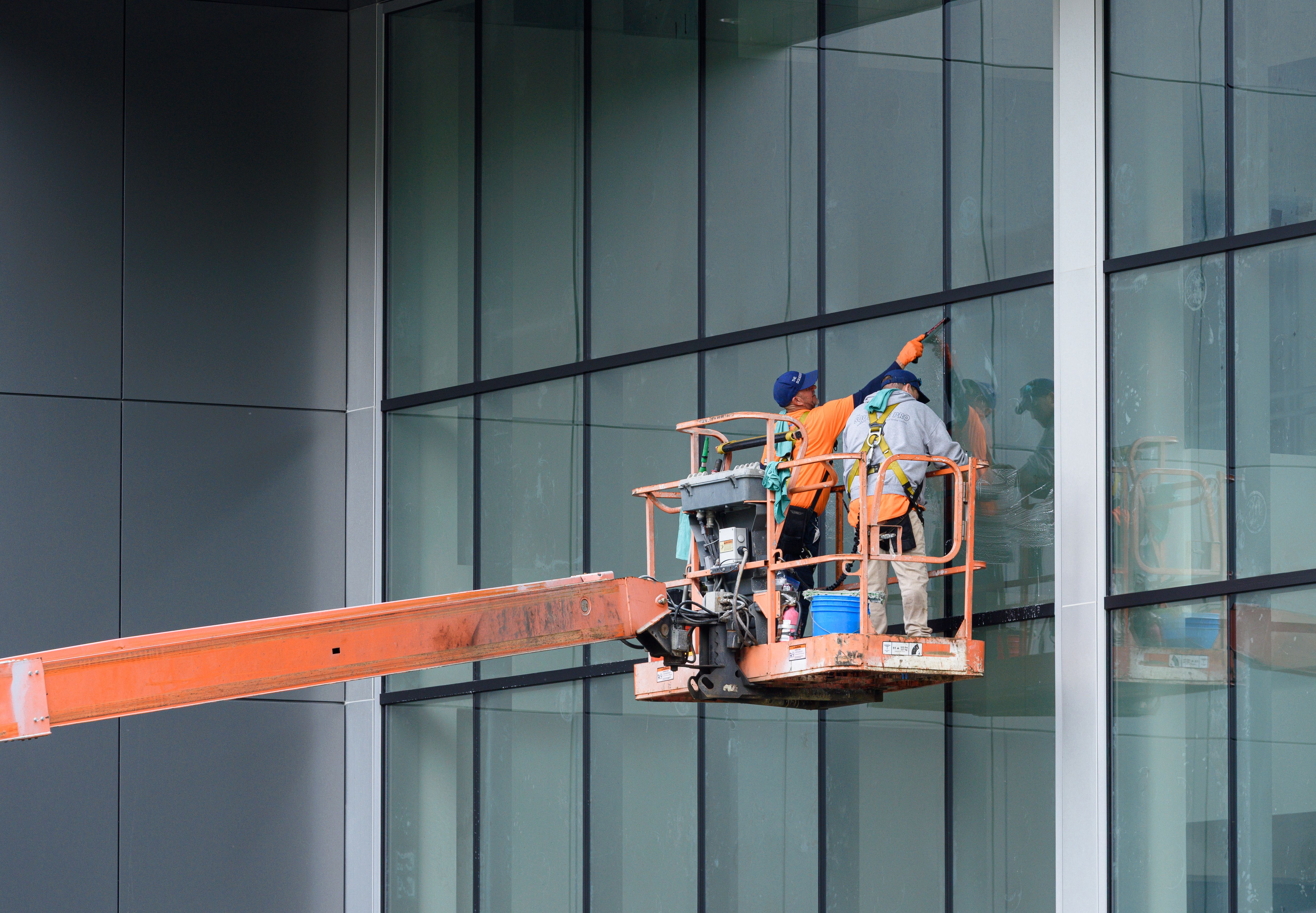 gratis Werknemers op een hoogwerker reinigen op veilige wijze de ramen van een modern hoogbouwgebouw. Stockfoto