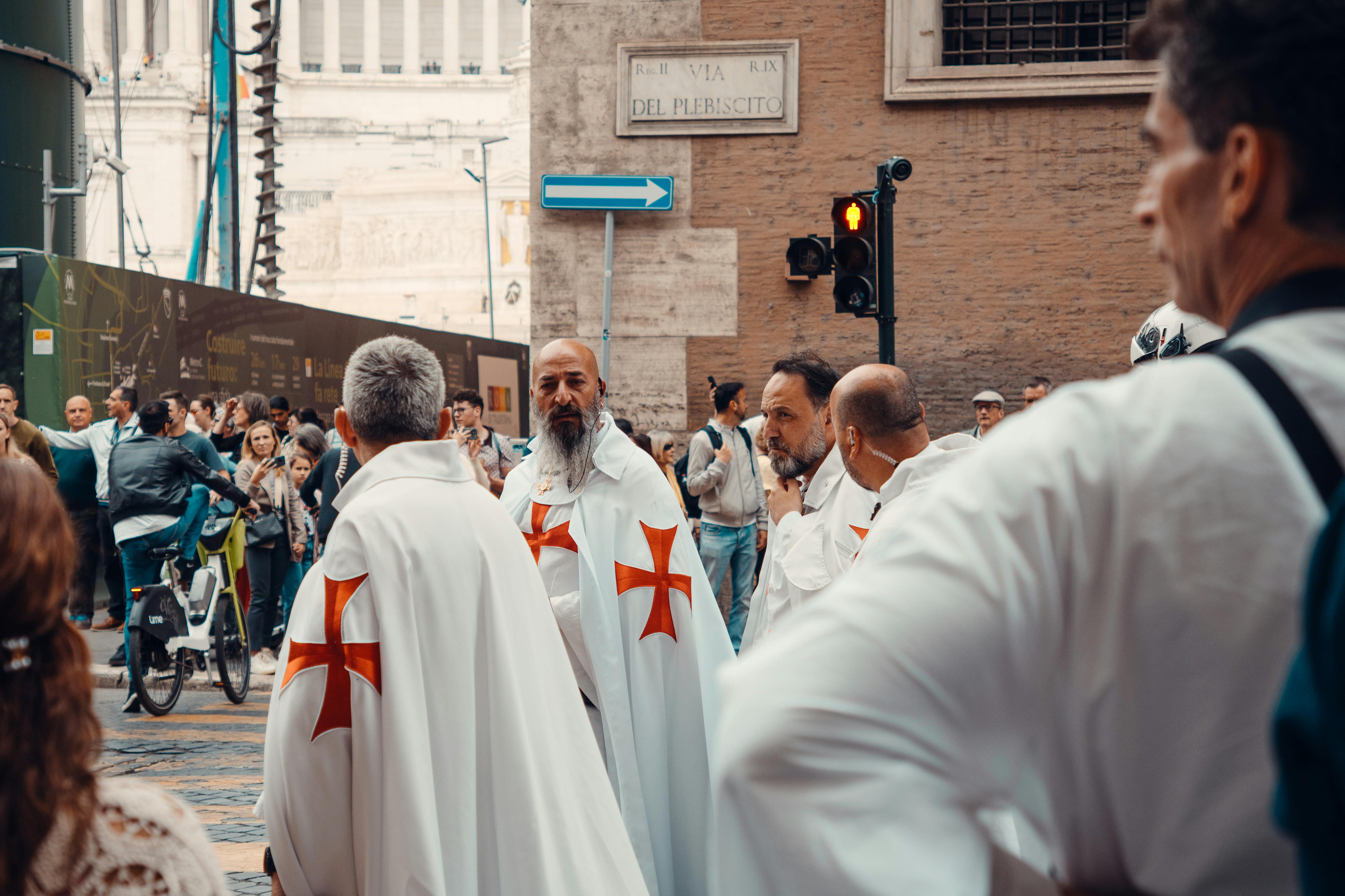 Men in ceremonial robes gather on a bustling street in Rome, Italy, showcasing historical traditions.