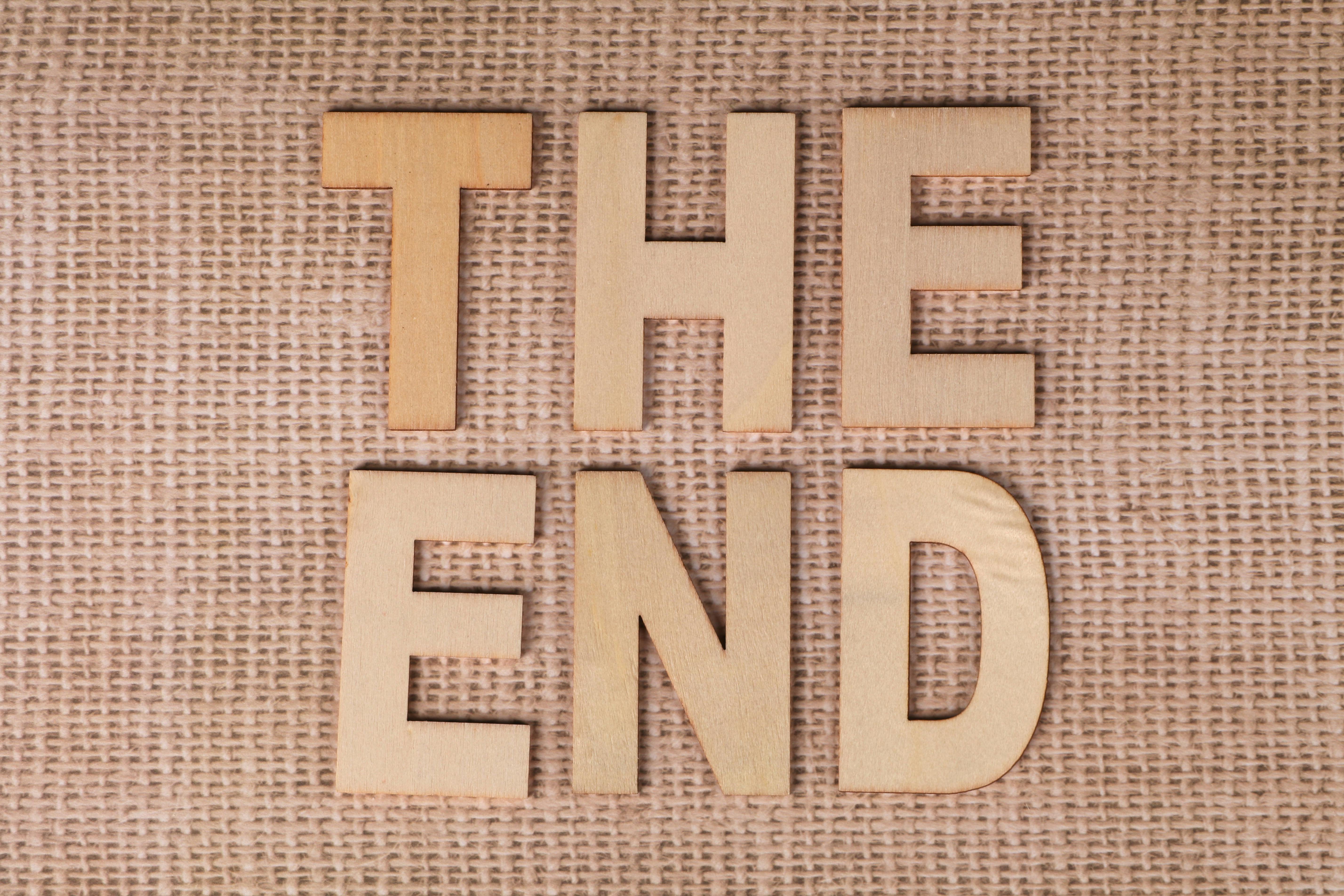 Wooden letters arranged to spell 'The End' on a burlap background.