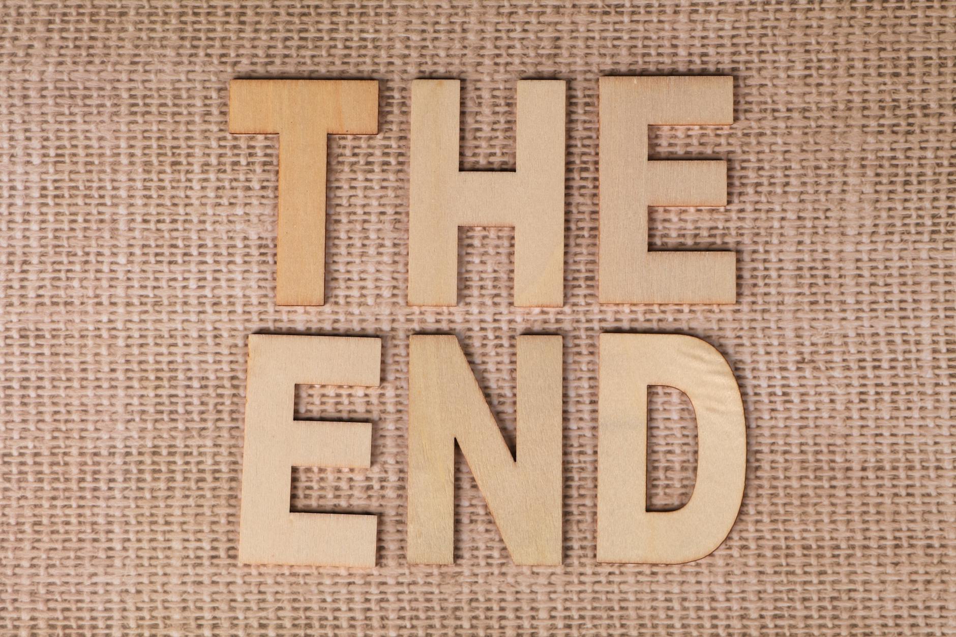 Wooden letters arranged to spell 'The End' on a burlap background.