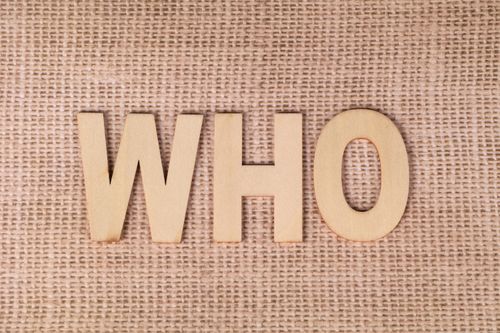Free Wooden letters spelling 'WHO' on a textured burlap fabric, emphasizing identity or inquiry. Stock Photo
