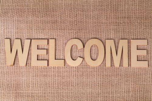 Free A wooden 'Welcome' sign laid on a textured burlap fabric surface, creating a rustic look. Stock Photo