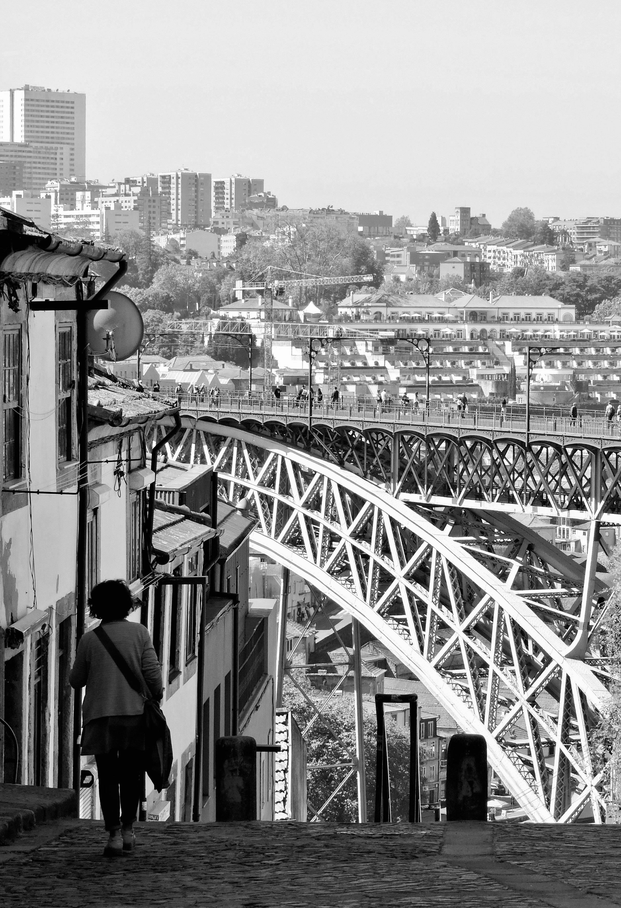 Black and white street view of Porto, featuring the iconic Dom Luís I Bridge.
