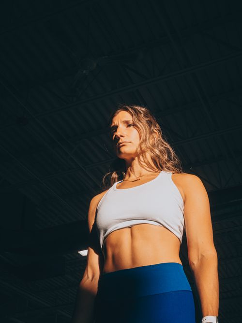Free Confident female athlete in gym showcasing strength and fitness under dramatic lighting. Stock Photo